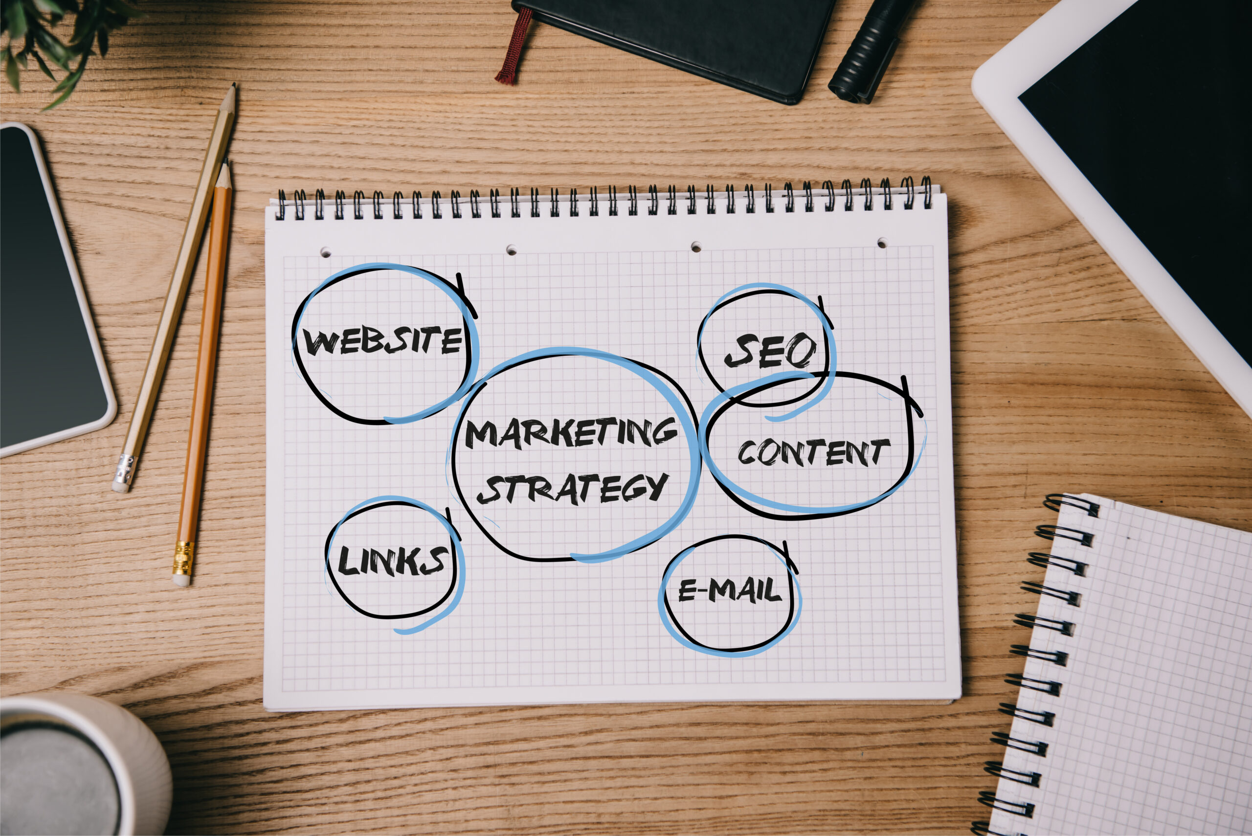 top view of business supplies, digital devices and notebook with marketing strategy on workplace